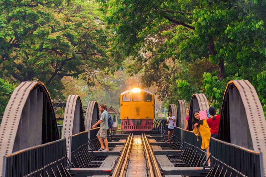 A train crossing a bridge with people walking on it. 5