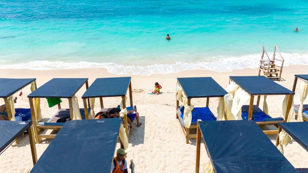 A beach with clear turquoise water, a lifeguard tower, and several beach umbrellas. 3