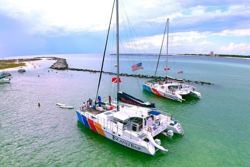Due barche a vela chiamate 'Island Breeze' ancorate vicino a un promontorio roccioso sotto un cielo sereno. 4
