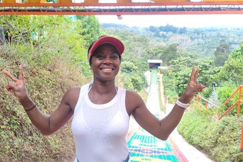 A person standing on a bridge with greenery and a distant structure in the background. 5