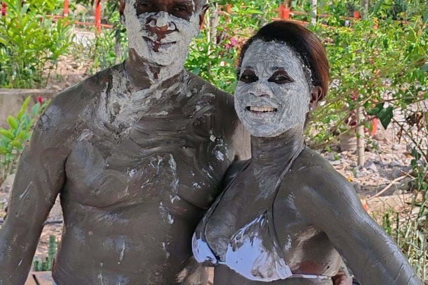 A person covered in a white substance, standing outdoors with greenery in the background. 2