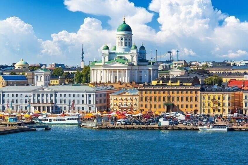 A waterfront cityscape with historic buildings, a prominent green-domed structure, and a busy harbor. 1