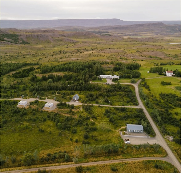 An aerial view of a rural landscape with rolling hills, scattered houses, and a winding road. 4