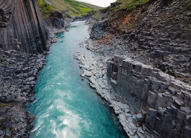 A river flowing through a rocky canyon with steep cliffs on one side and a rocky wall on the other. 3