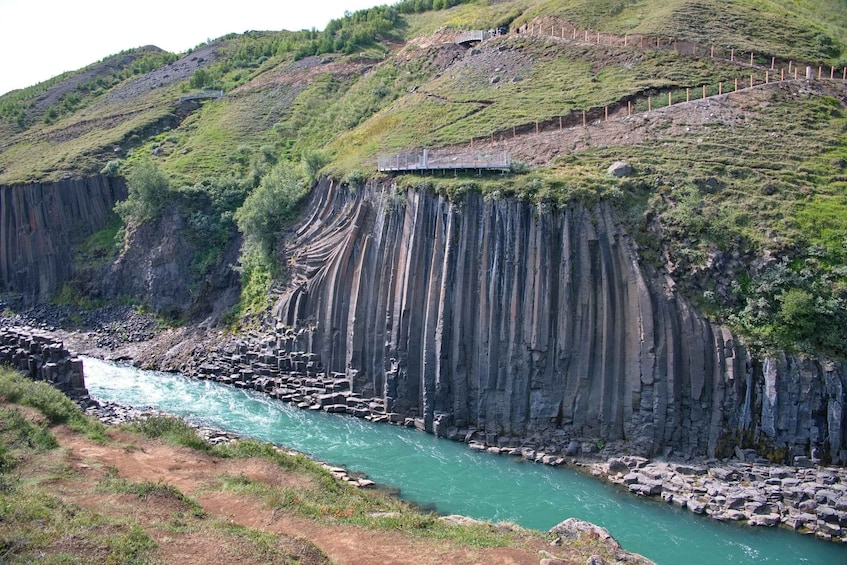 A river flowing through a canyon with steep, rocky cliffs and a small structure on the hillside. 1
