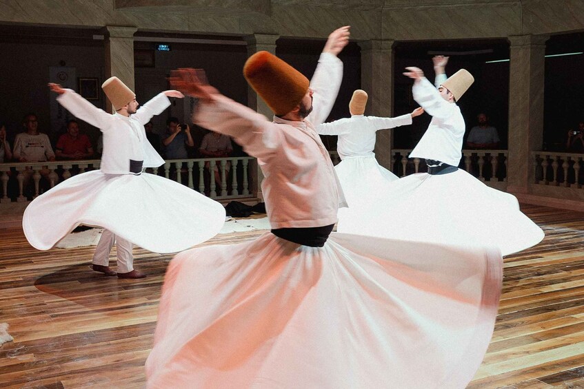 A dance performance with dancers in white attire and traditional hats. 2