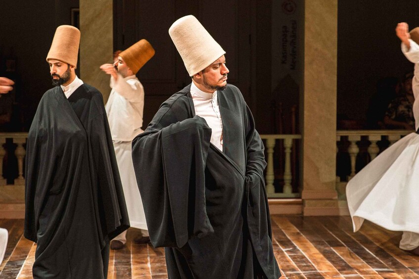 Individuals in traditional attire, including tall hats and robes, in a formal setting with a tiled floor and classical architecture. 3
