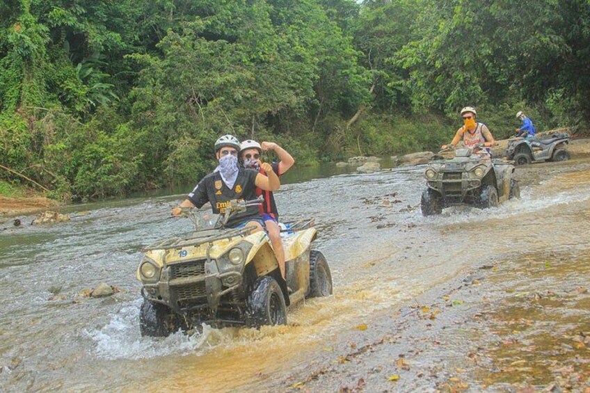 Menschen fahren mit Quads auf einem Fluss, umgeben von dichtem Grün. 4