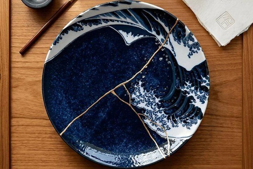 Un plato de cerámica azul y blanco con una grieta, sobre una superficie de madera. 3