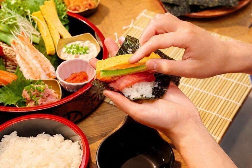 Une personne préparant des sushis avec du riz, du poisson et des légumes. 1