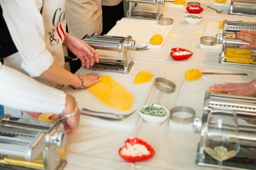 People preparing food with pasta, lemons, and bowls on a table. 2
