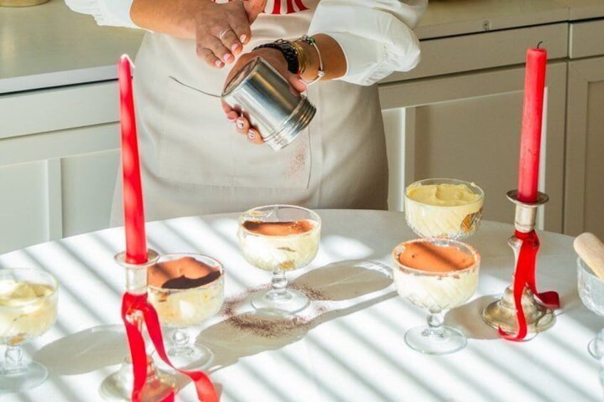 A person pouring a liquid into a dessert on a table with red candles. 3
