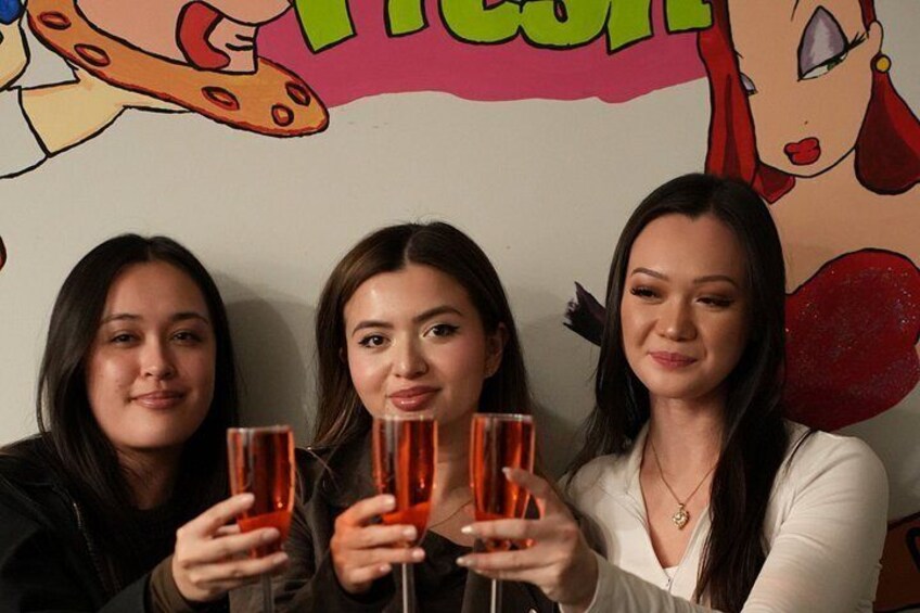 Tres personas sosteniendo vasos con una pared colorida al fondo. 4