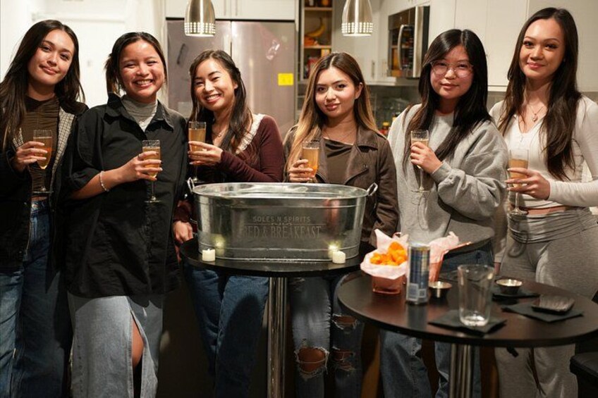 Un grupo de personas de pie alrededor de una mesa con bebidas y un recipiente grande. 1
