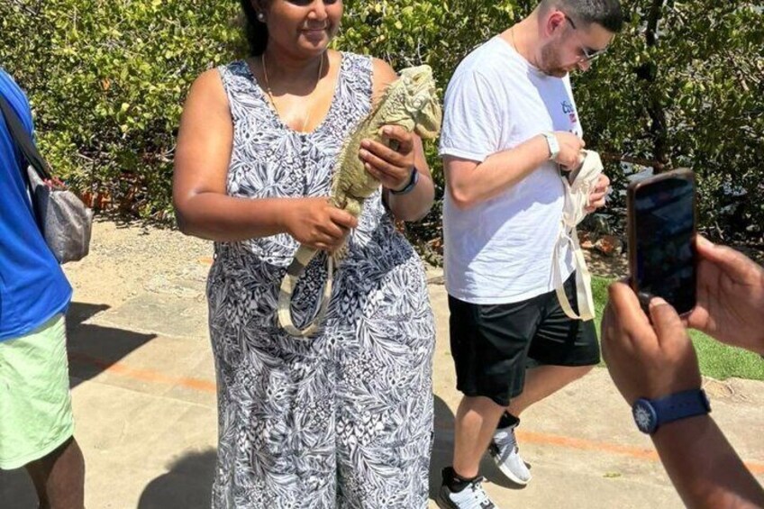 A person holding a small animal, possibly a lizard, in a patterned dress, with another person in the background. 2