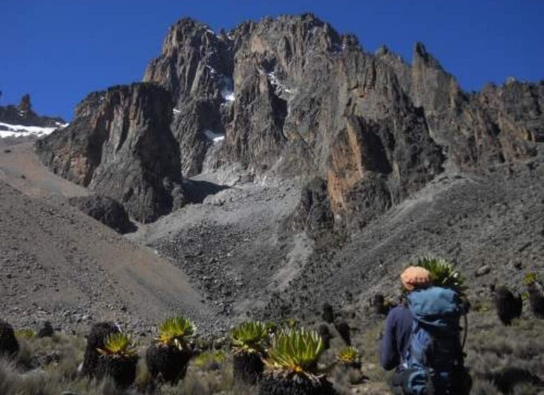 A hiker with a backpack in a rocky mountainous area with sparse vegetation. 5