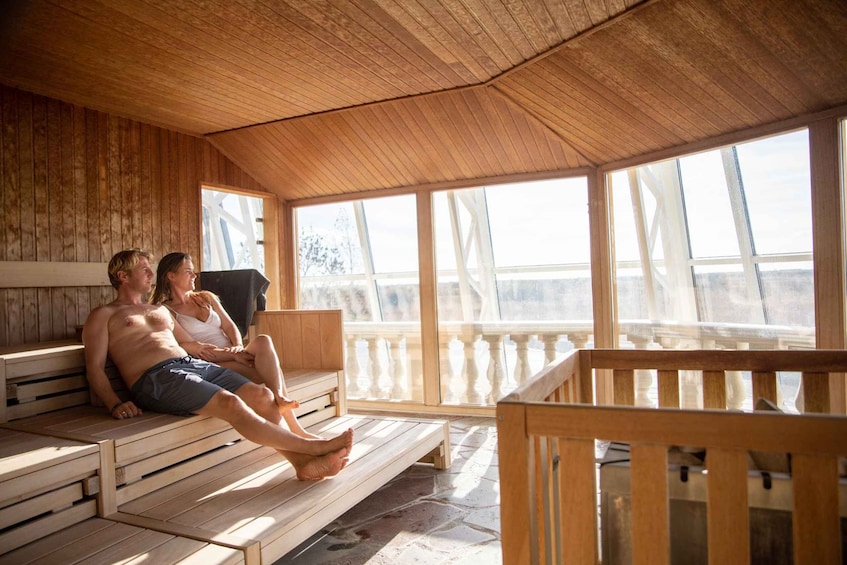 A wooden sauna with benches and a balcony overlooking a snowy landscape. 2