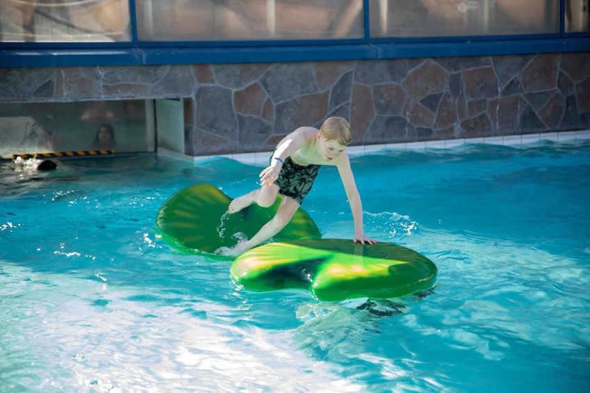 A person riding a green watercraft in a swimming pool. 3