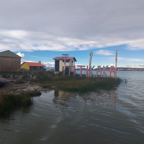 A waterfront with buildings, a dock, and a cloudy sky. 1