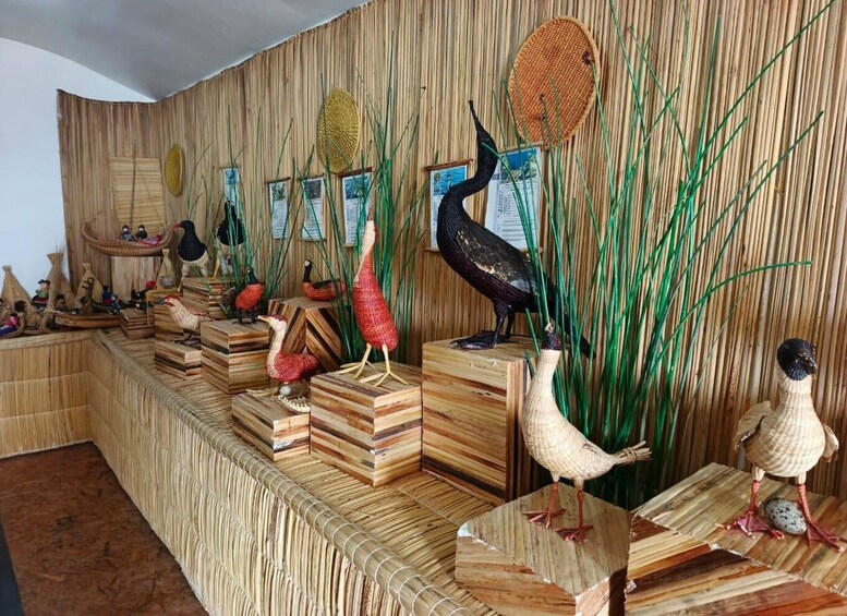 A display of bird sculptures on wooden platforms against a bamboo backdrop. 3