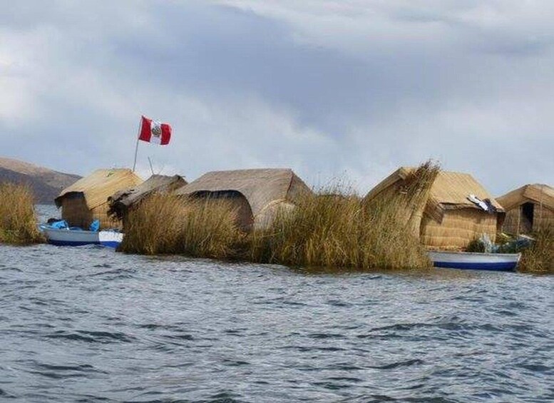 Thatched-roof huts on stilts in a body of water, with a Canadian flag visible. 2