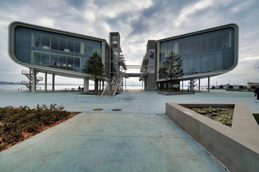 A modern building with a curved glass facade, a central staircase, and a waterfront view. 2