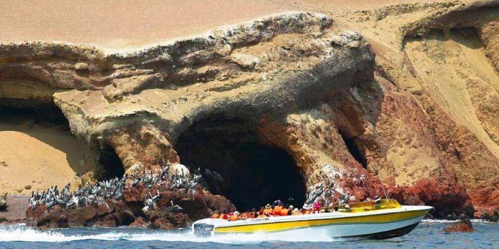 A boat with passengers near a rocky coastline. 2