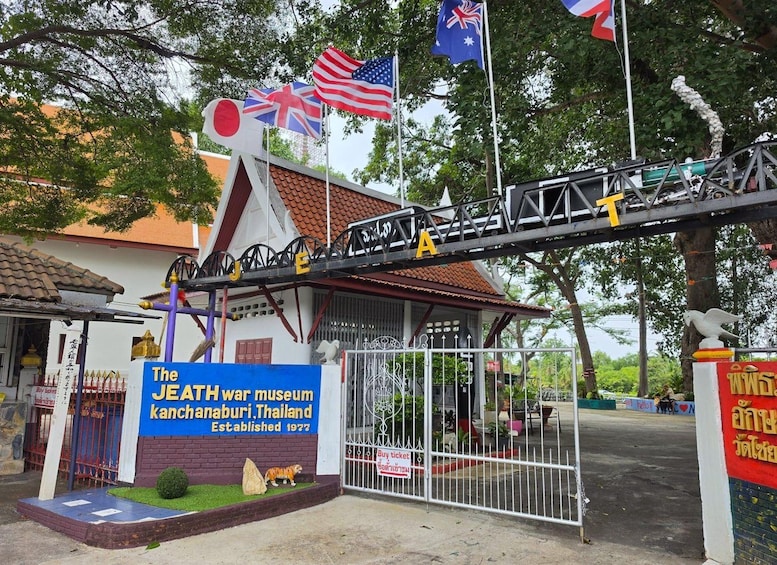 The JEATH War Museum entrance with flags, a sign, and a tiger statue. 4