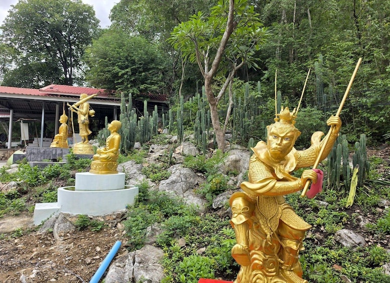 Golden statues of figures in various poses, set against a backdrop of cacti and trees. 3