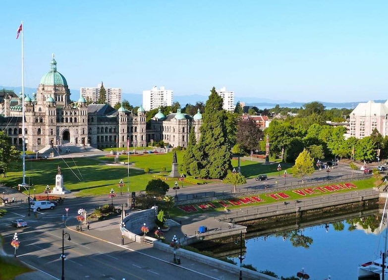A cityscape with a prominent government building, a waterfront promenade, and a clear sky. 1