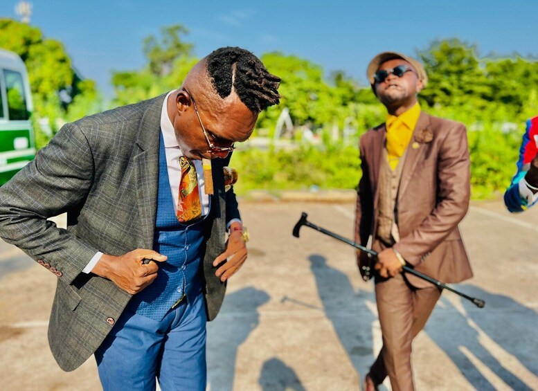 Two men in suits, one adjusting his tie, and another holding a walking stick. 4