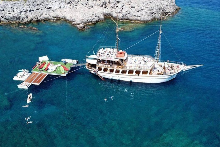 Un barco grande amarrado cerca de una costa rocosa con agua azul cristalina. 1