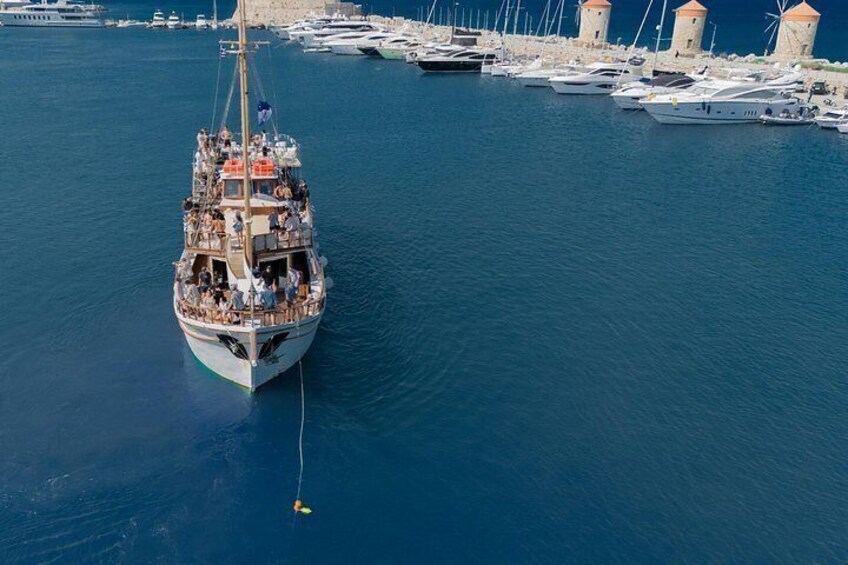 Un velero grande amarrado en un puerto deportivo, con varios barcos más pequeños y dos torres al fondo. 4