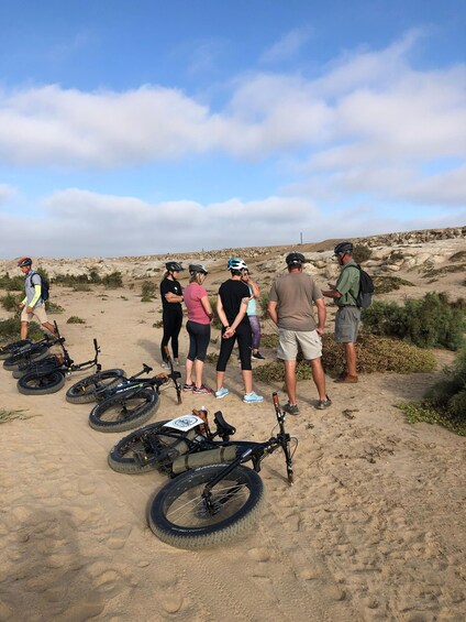 A group of people with bicycles and helmets in a desert landscape. 4