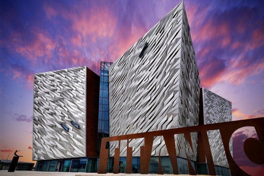 A modern building with a unique geometric facade, set against a vibrant sunset sky. 2