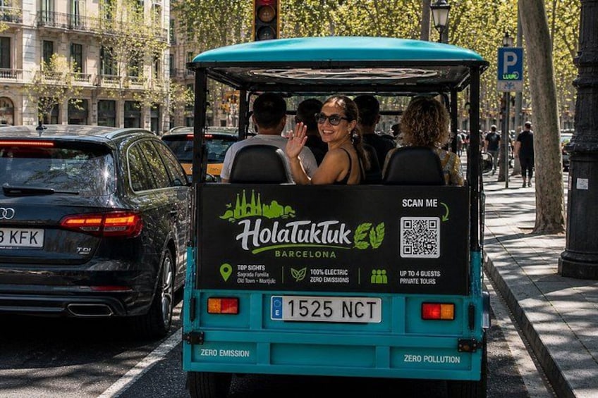Un veicolo turistico elettrico color petrolio con passeggeri, parcheggiato in una strada cittadina. 3