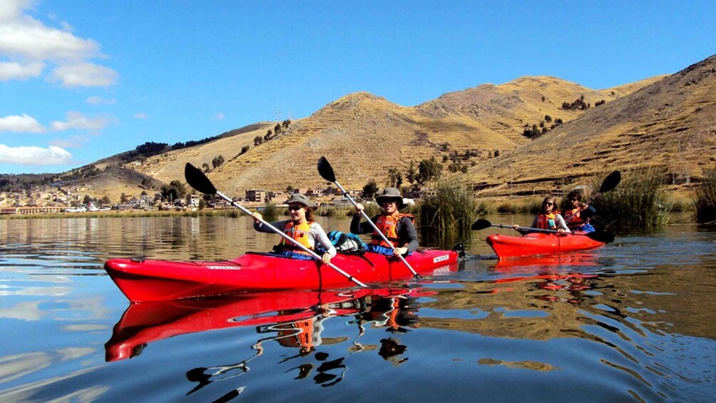 A group kayaking on a calm lake with mountains in the background. 2