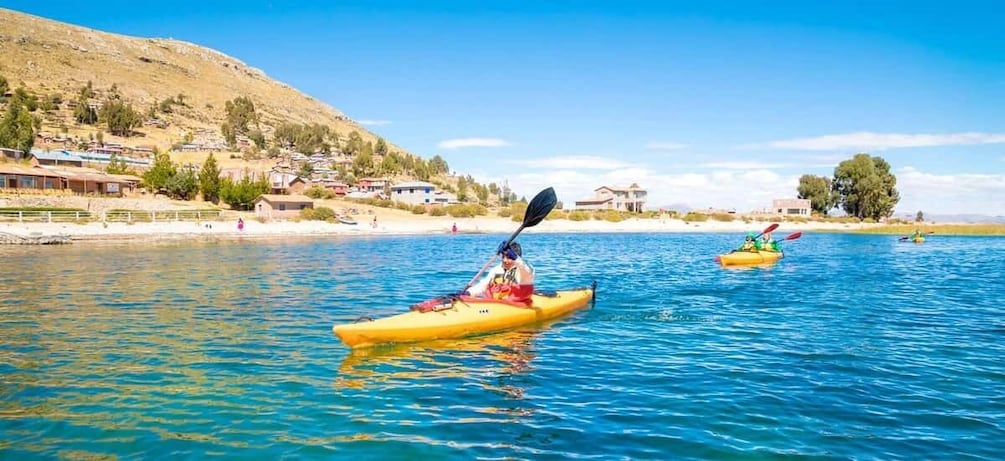 Two kayaks on a calm body of water with a hilly landscape in the background. 1