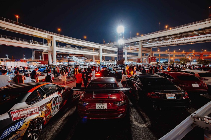 A nighttime urban scene with a busy street, multiple vehicles, and a prominent bridge structure. 2