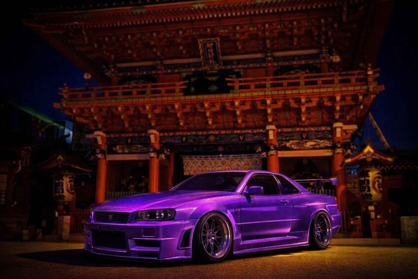 A purple sports car parked in front of a traditional Asian building at night. 3