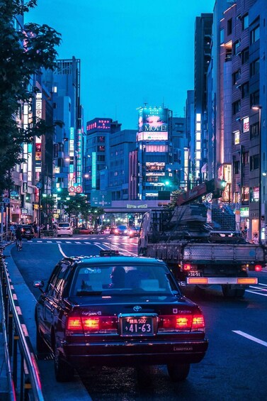 A busy urban street at dusk with neon signs and a taxi. 5