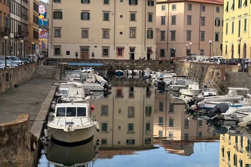 Ein Yachthafen mit vertäuten Booten, ein Kanal und Gebäude im Hintergrund. 2