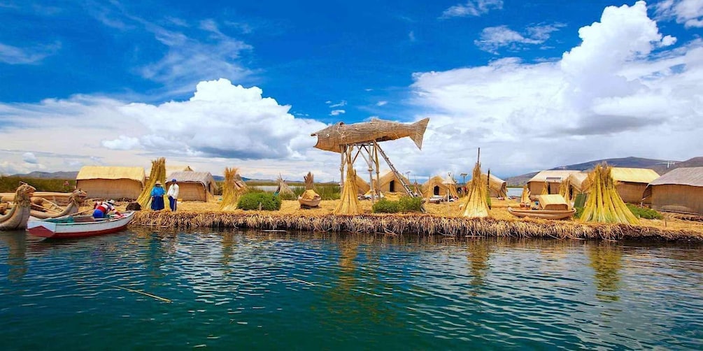 A traditional village by a lake with thatched-roof huts and a large wooden structure. 1