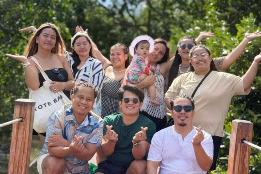 Un grupo de personas posando sobre un puente de madera con follaje al fondo. 3