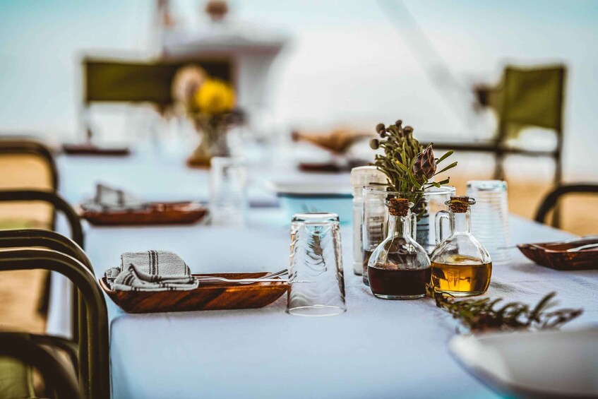 A table set with glassware, a bottle of olive oil, and a small plant. 3