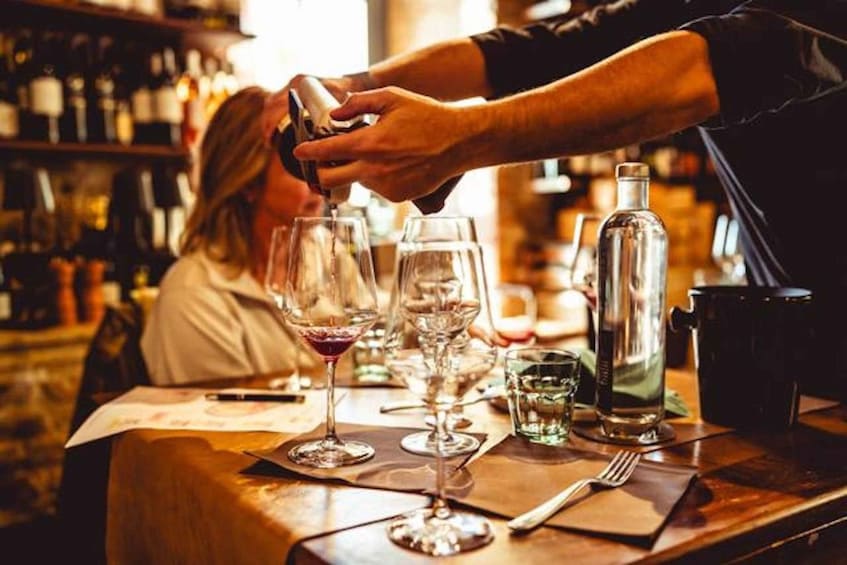 A bartender pouring a drink into a wine glass at a bar. 3