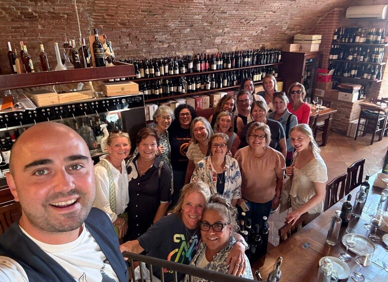 A group of people in a wine cellar with shelves of wine bottles. 5