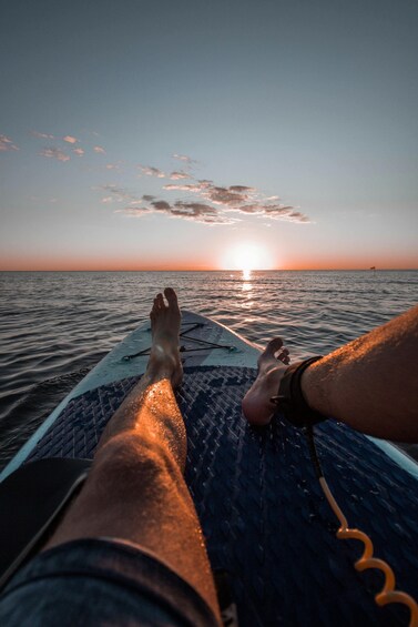 A person's legs on a boat with the sun setting in the background. 1