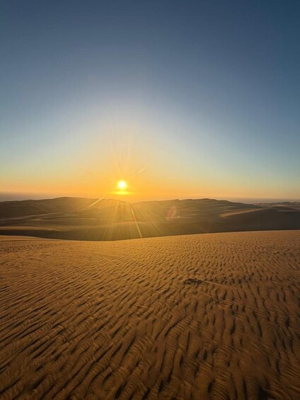 A desert landscape with sand dunes and a setting sun. 5