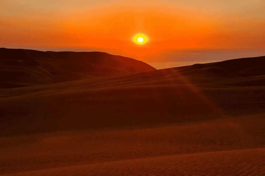 A desert landscape with sand dunes and a setting sun. 5